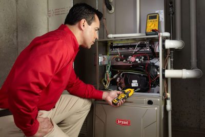Heating and air conditioning technician servicing an indoor furnace in Longmont, CO